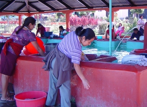 women washing at large compartmented laundry basin
